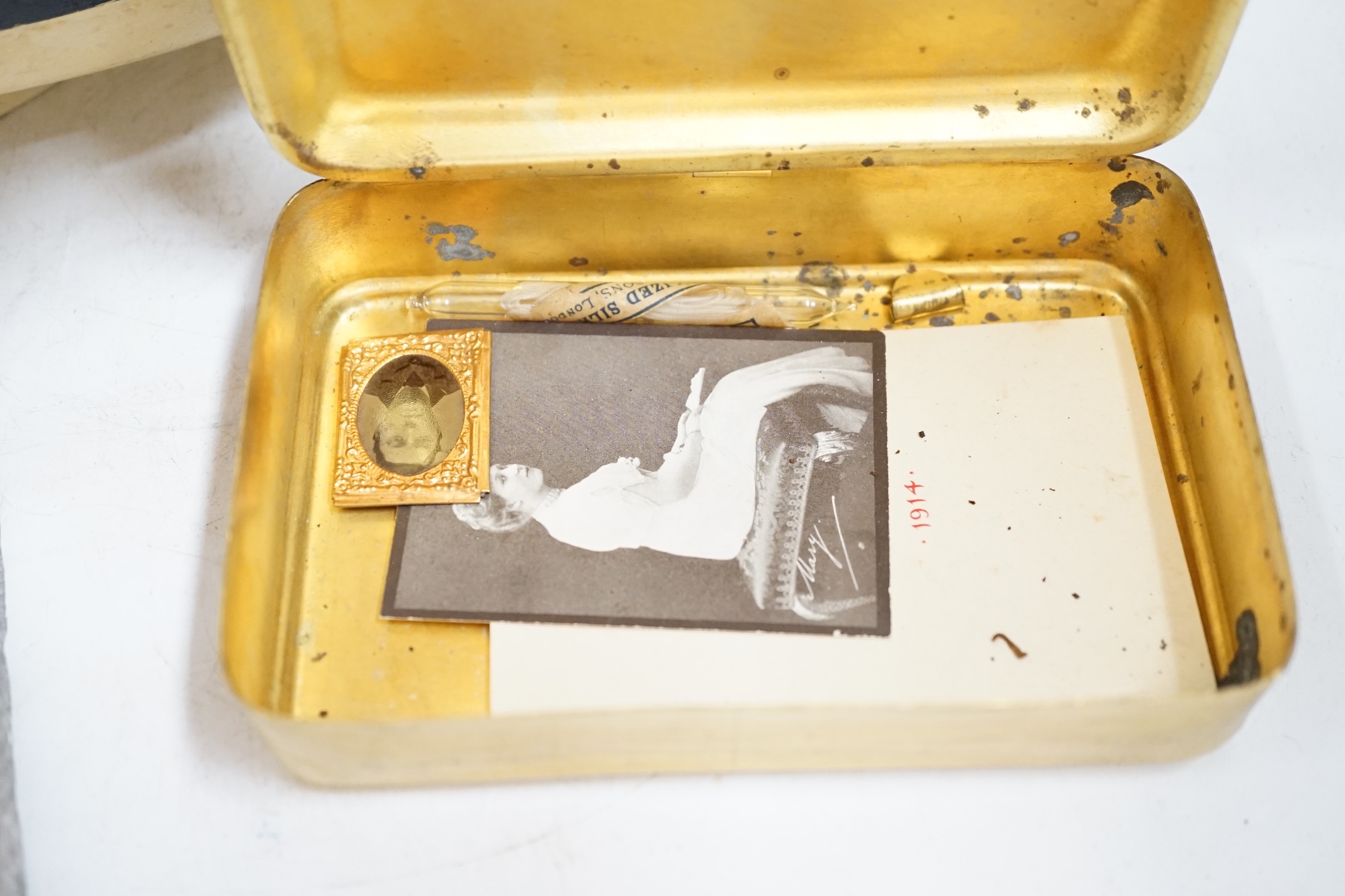 An RNLI sheet metal collecting box in the form of a lifeboat, together with a First World War Princess Mary Christmas tin containing the original tobacco, greetings card, photograph, and other items, plus two early 20th